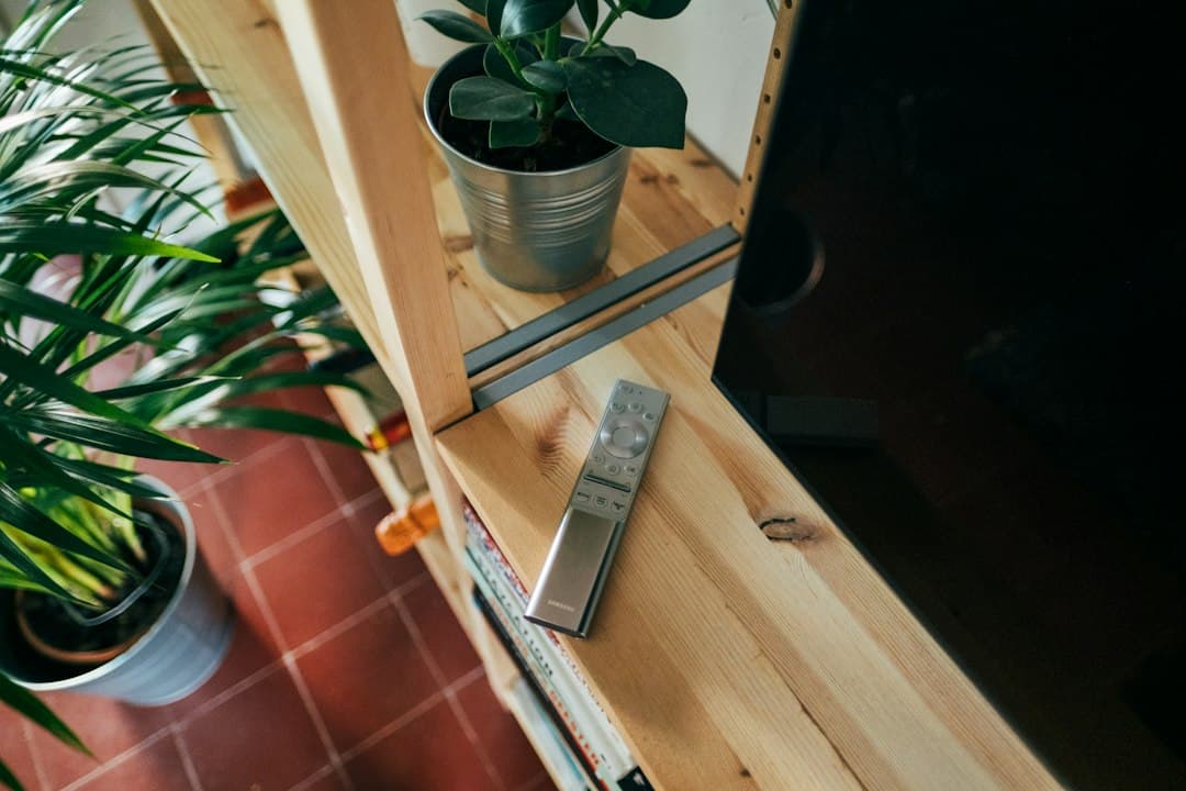 Télécommande posée sur une étagère en bois près d'un téléviseur